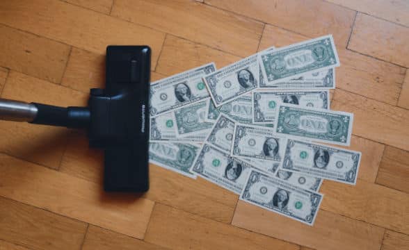 a-vacuum-cleaner-sucking-in-dollar-bills-from-a-wooden-floor