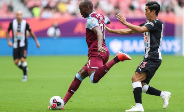 west-ham-player-keeps-the-ball-running-as-he-is-challenged-by-another-player-behind-him