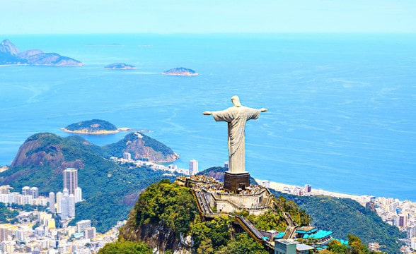 An aerial view of Rio de Janeiro during the day with the statue of Christ the Redeemer overlooking the city.