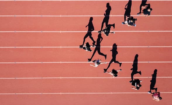 Athletes running on a track forming a triangle as they run