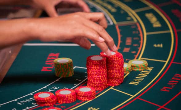 A live dealer adjusting the chips on a baccarat table in a real casino.