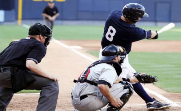 A baseball player is batting away a ball throw by a pitcher.