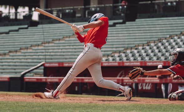 A baseball player in red taking a swing with his bat.