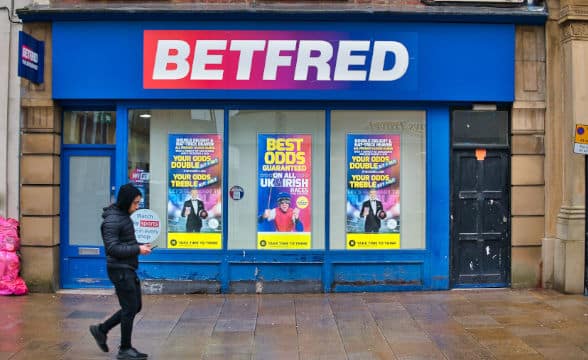 A pedestrian walking outside a Betfred shop.