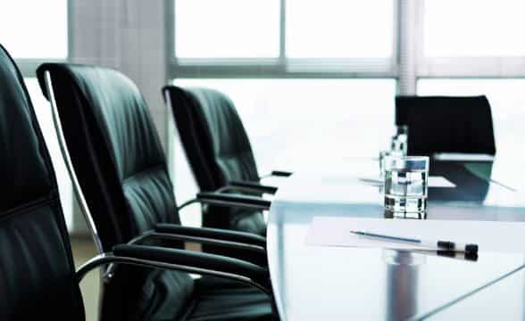 An empty room of board of directors with leather chairs and glass table.