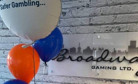 A wall with a sign with the Broadway Gaming logo.