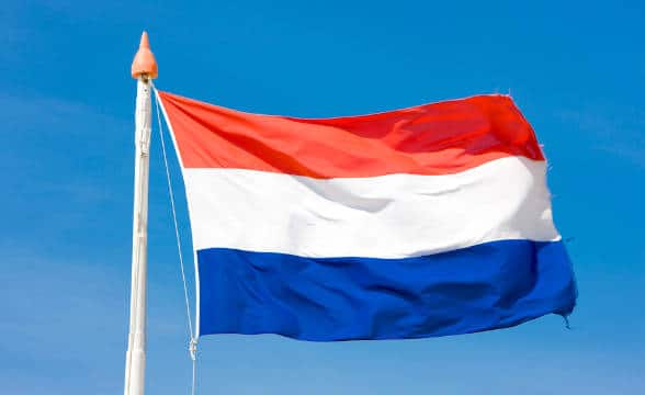 The Dutch national flag flying int he blue skies.