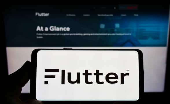 Flutter Entertainment's logo on a smartphone against a monitor background.