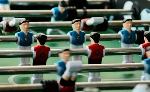 A foosball table with two teams in red and blue playing against each other.