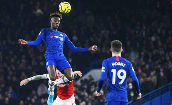 A former player from Chelsea FC receiving a pass near his teammates and an opponent.