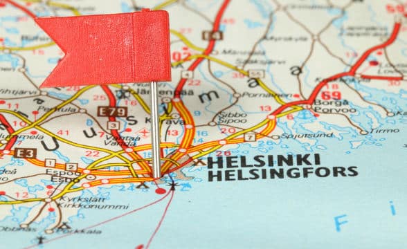 A flag pinned to a map showing the capital of Finland, Helsinki.