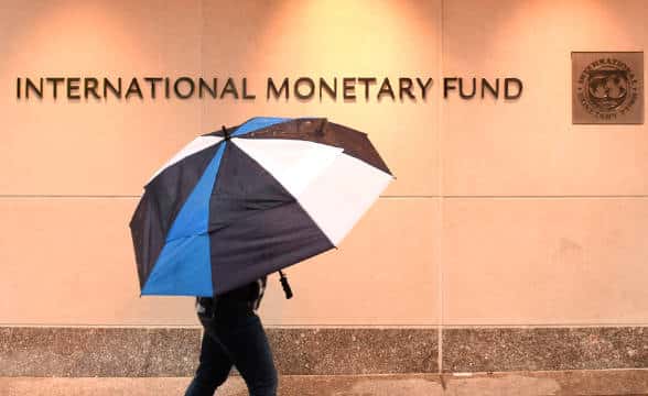 A pedestrian with an umbrella walking outside an IMF building.