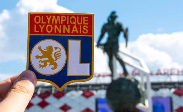 A man holding a Lyon symbol in front of the local stadium in France.