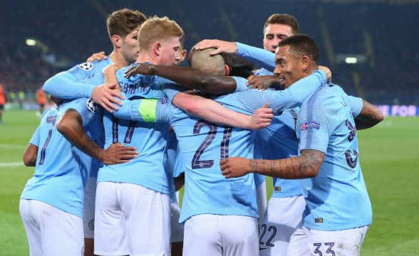 A group of Manchester City players gathering together after a successful goal.