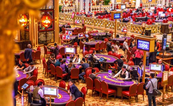 People in a casino in Macau playing various table games, including baccarat, blackjack and so on.