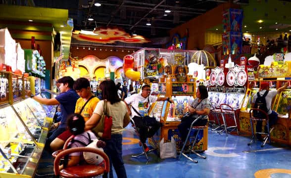 A bunch of gamblers in the Philippines playing at arcade machines.