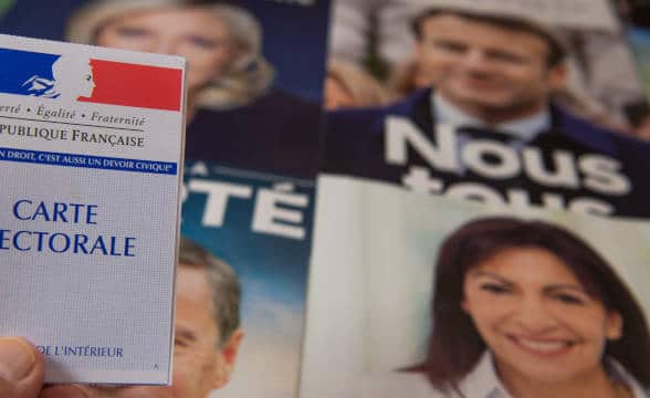 The candidates for the French presidency with a person holding an electoral card in front of their images.