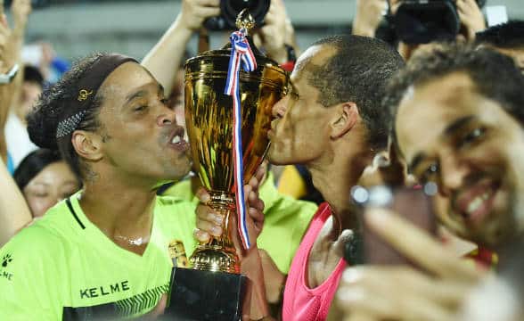 Ronaldinho celebrating another soccer victory, kissing a trophy with his teammates