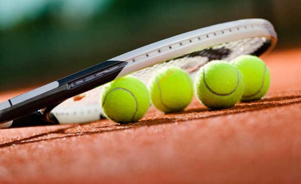 A tennis lying on the ground with three balls.