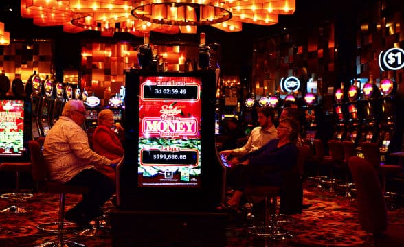 The inside of the Crown Casino in Melbourne, Australia. People sitting at slot machines and playing.