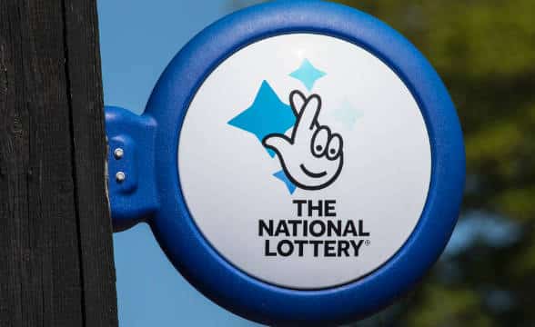 Camelot's National Lottery logo and sign in the United Kingdom on a building, probably next to a lottery outlet.