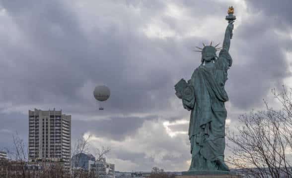 New York and the Stature of Liberty seen from behind in the cloudy skies.