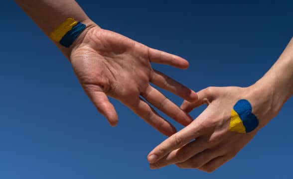 Two people holding hands with Ukraine's national flag on them.