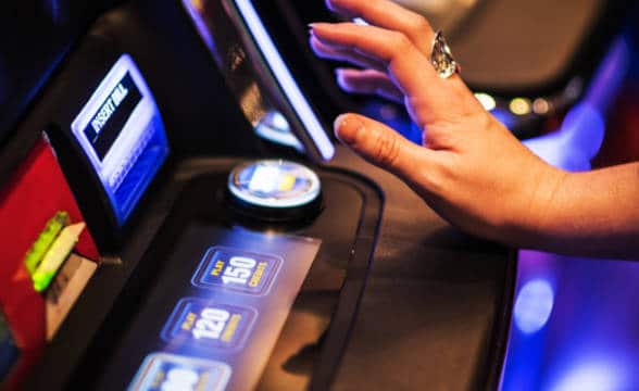 A woman at a gambling machine about to press the button to play.