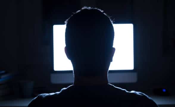 A man sitting up in front of a computer late.