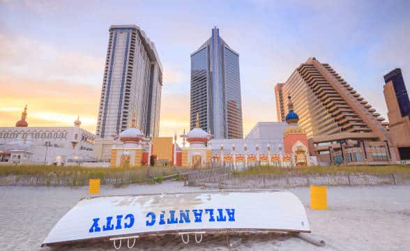 Atlantic City's casinos in the sunrise with a boat flipped over on the beach in front of said casinos.