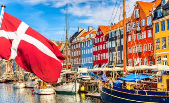 Danish flag flying against a background of yachts and boats.