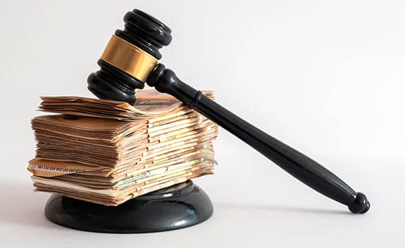 A judge's hammer sits on a stack of money