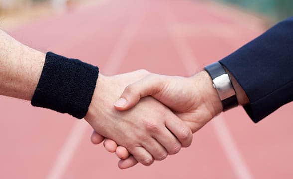 A sports player and a businessman shake hands