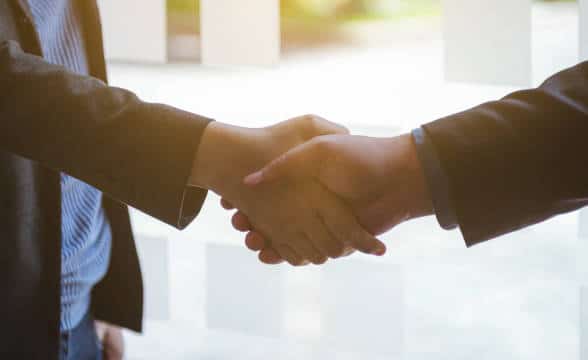 Two people shaking hands as they agree to a business deal.