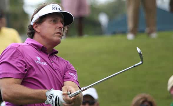 Phil Mickelson taking a swing on a golf course.