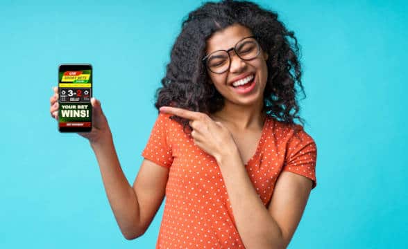 A woman pointing at her betting wini that shows up on her smartphone.