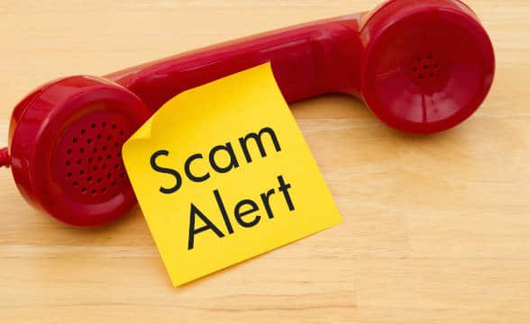 A read phone head with a sticky note that says Scam Alert.