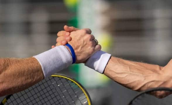 Two tennis players clasping hands.