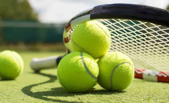 Tennis rackets and balls on a green felted court for tennis.