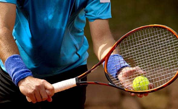 A tennis player holds a ball and a racquet