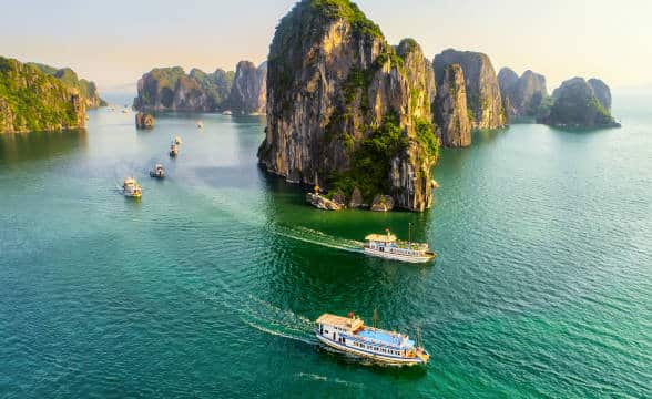 Vietnamn toursit boats in the water around beautiful landscapes.