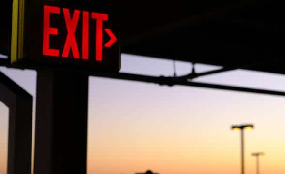 An exist sign in an urban area, possibly a train station at dusk.