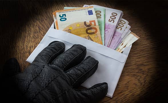 A criminal holds an envelope full of money