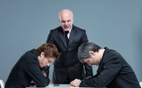 Two people looking down in shame while being told off