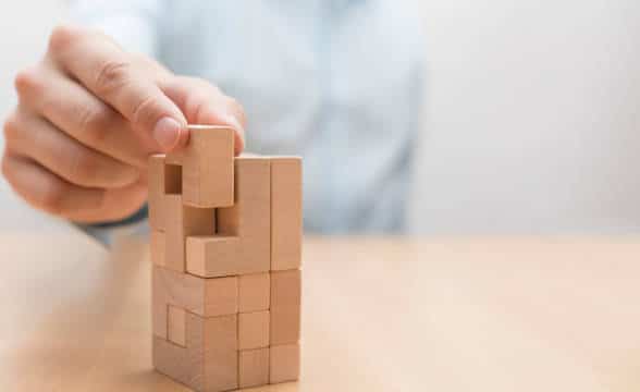 A janga-like piece being added to a cube tower.