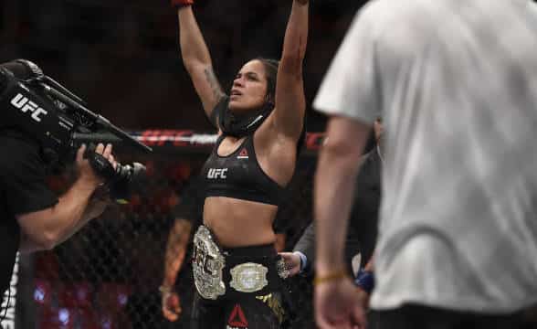 Amanda Nunes waving hands victorious.