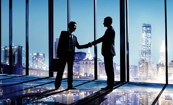 Two businessmen shake hands in an office.