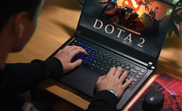 A gamer plays Dota 2 on a laptop