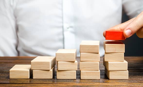 A person stacks blocks in progressively taller stacks.