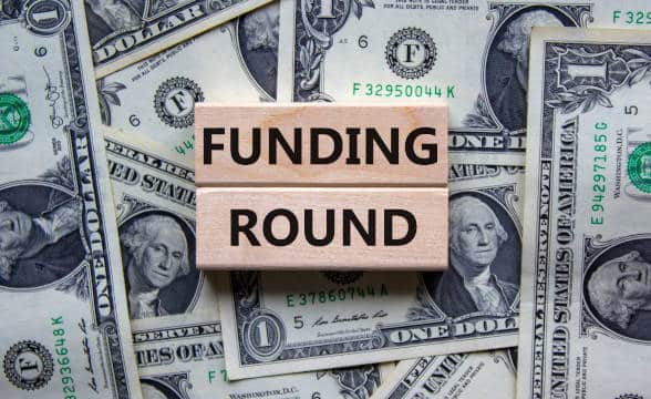 The words "funding round" on two pieces of wood against a backdrop of US dollars.